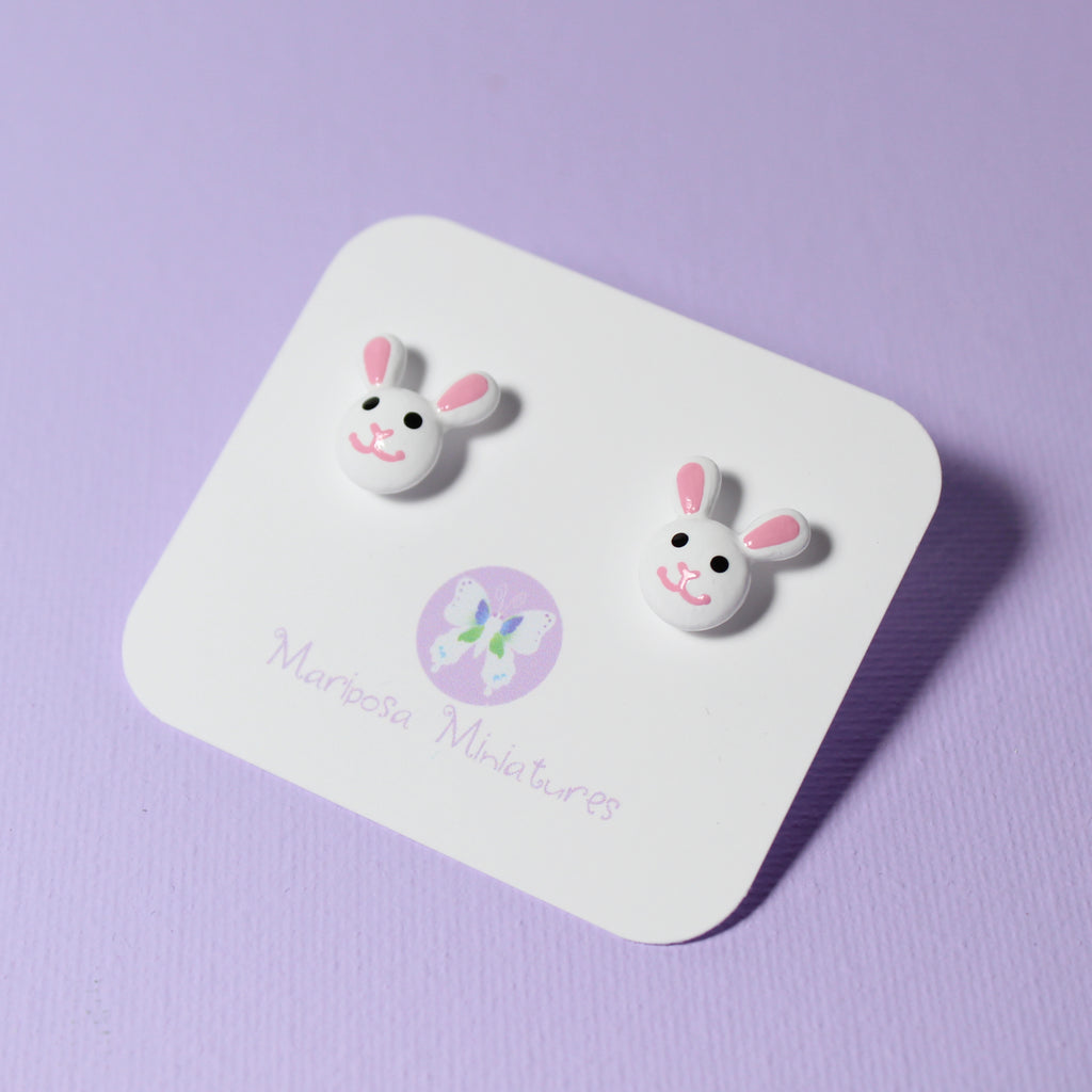 A pair of bunny stud earrings are displayed on a white jewelry backing card