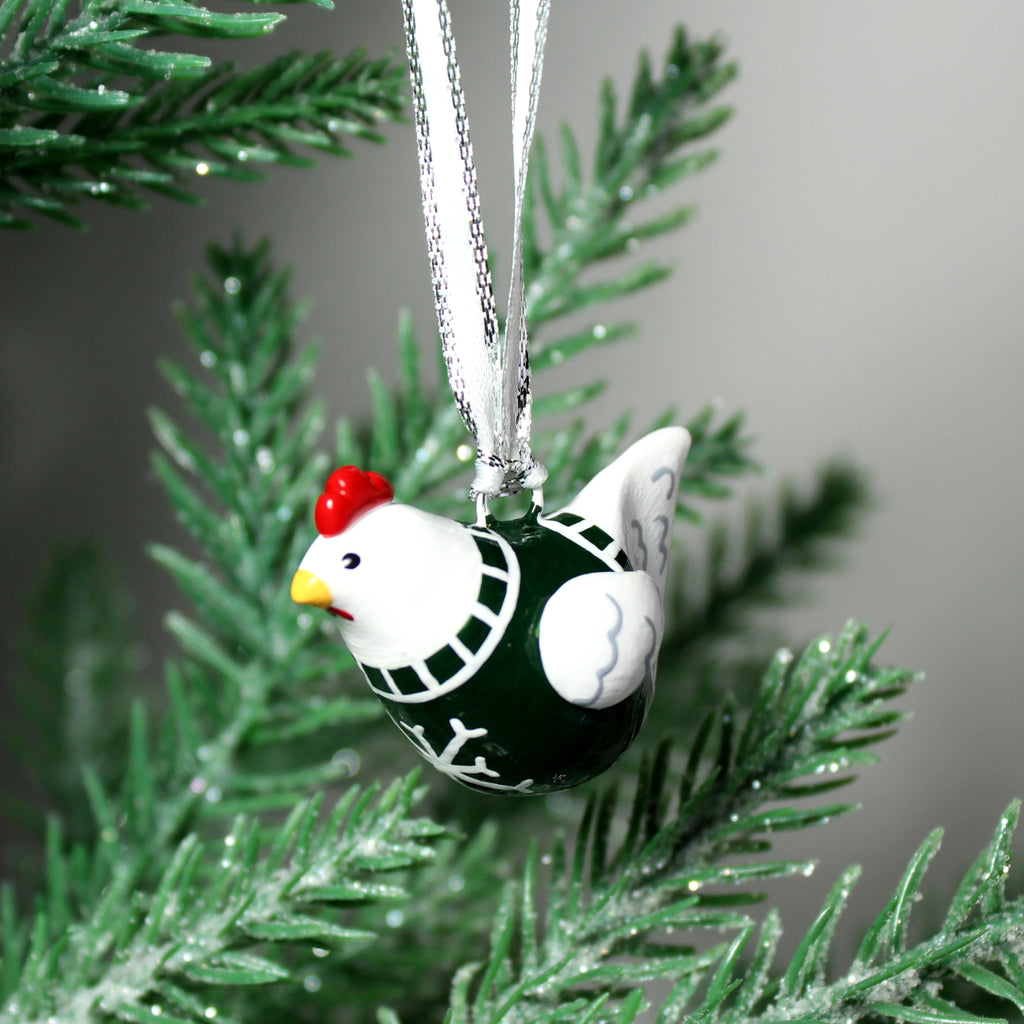 A white hen ornament with a green snowflake sweater hangs from a silver ribbon