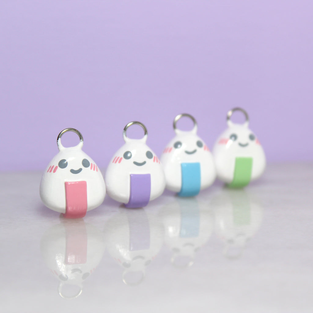 Four onigiri charms with pastel nori lined up in a row.
