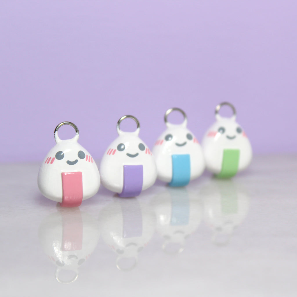 Four onigiri charms with pastel nori lined up in a row.