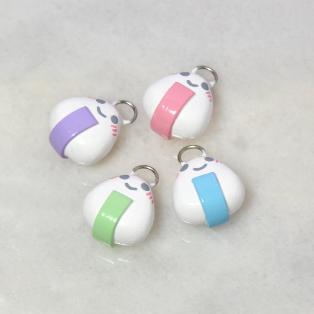 Four onigiri charms lying on a marble tile.
