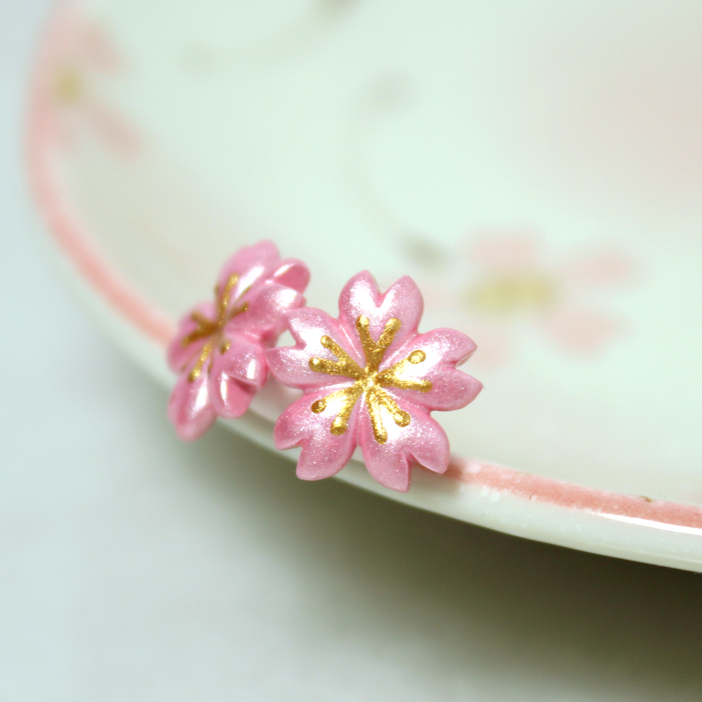 A pair of cherry blossom earrings rest against a jewelry dish.