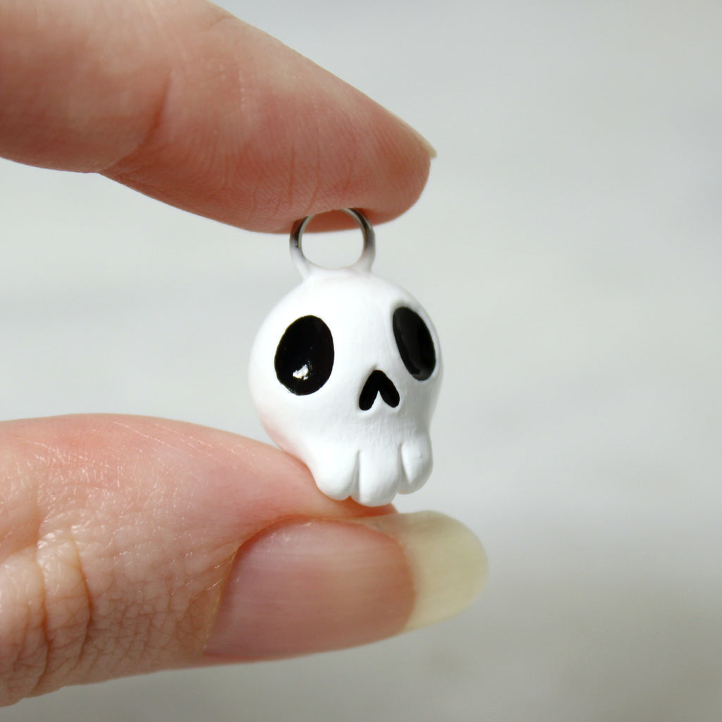 A hand holds a miniature skull charm