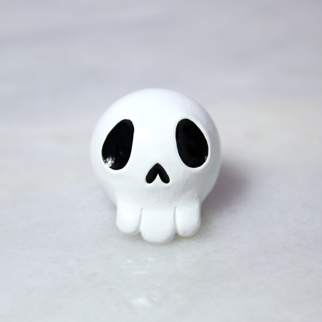 A miniature white skull figurine with black empty eye sockets