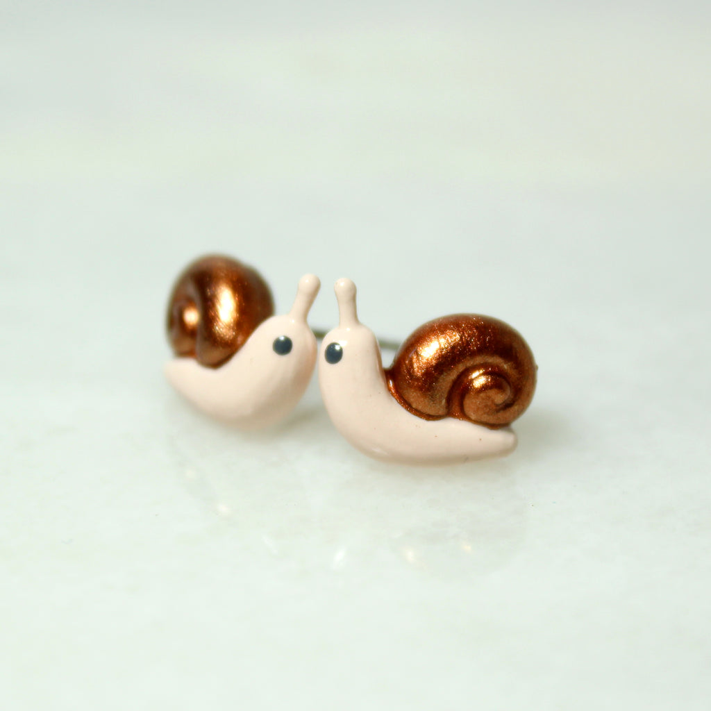 A pair of snail stud earrings with sparkly bronze shells