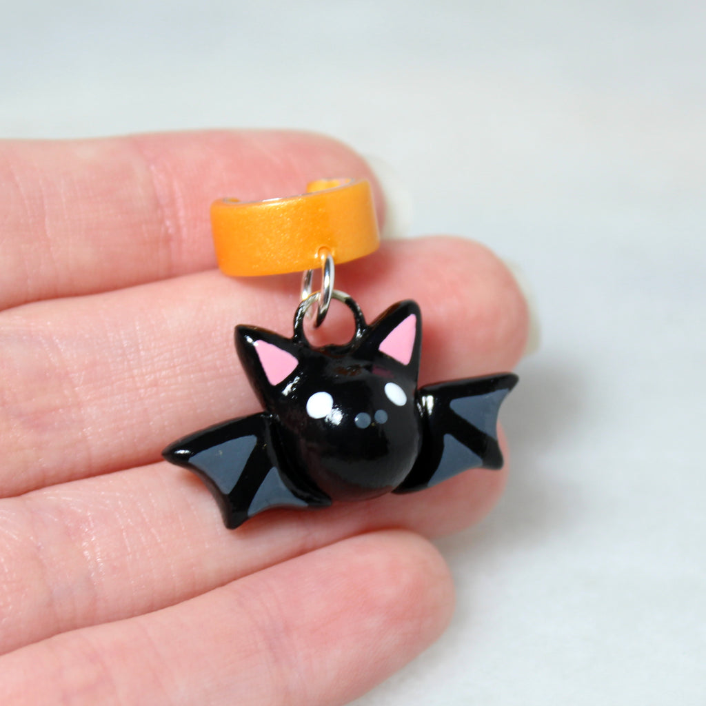 A hand holding a bat ear cuff. The bat charm is about 3/4 of an inch tall.
