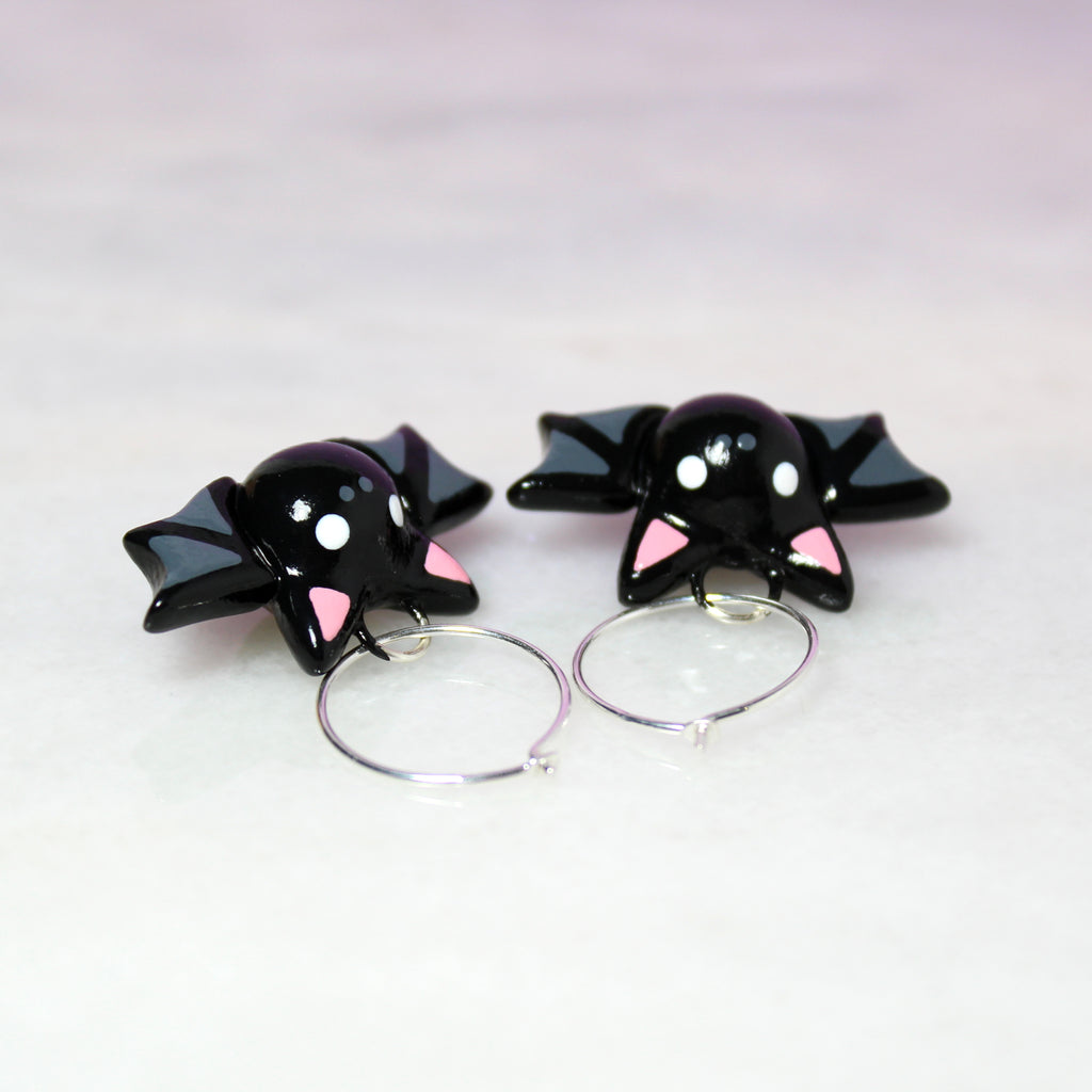 Top view of a pair of bat hoop earrings. The earring hoops are .925 grade sterling silver and are 19mm wide.