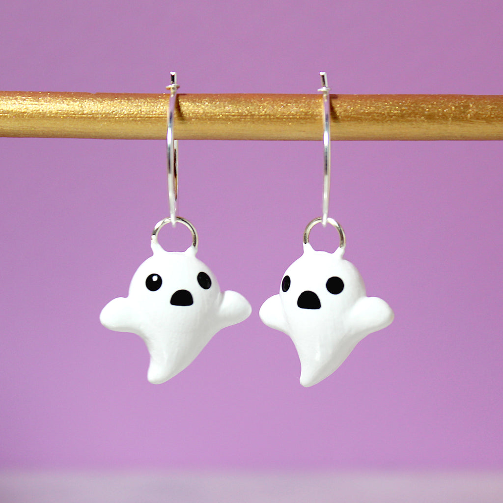 A pair of ghost hoop earrings hanging from a golden bar. The hoops are 19mm wide and sterling silver.