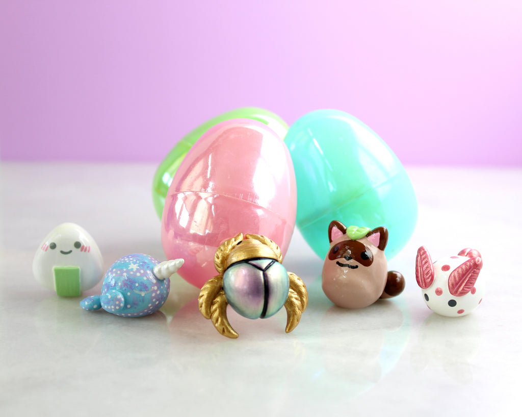 An assortment of figurines surround three iridescent plastic easter eggs.