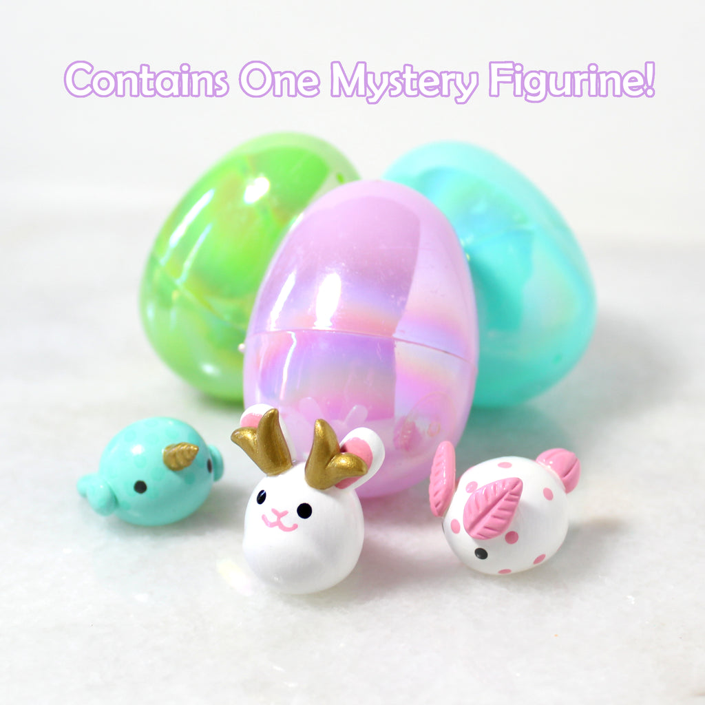 Three miniature figurines sit in front of three iridescent plastic easter eggs. Text reads: Contains One Mystery Figurine!