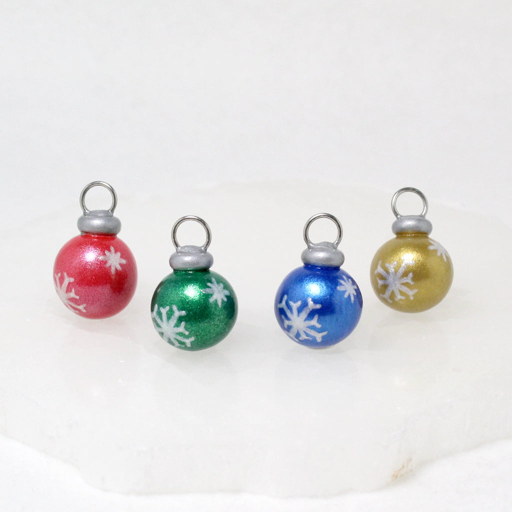 Four mini christmas ornament charms with sparkly snowflake designs.