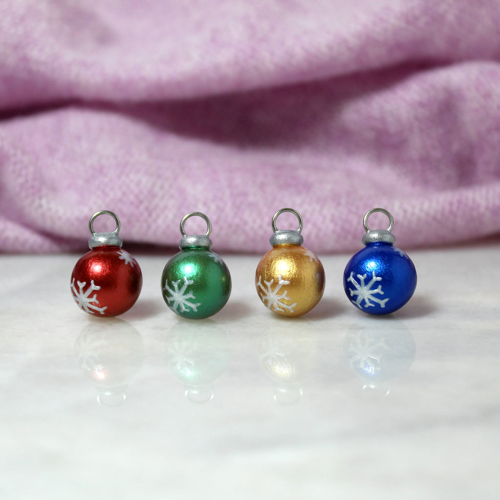 Four mini christmas ornament charms with sparkly snowflake designs.